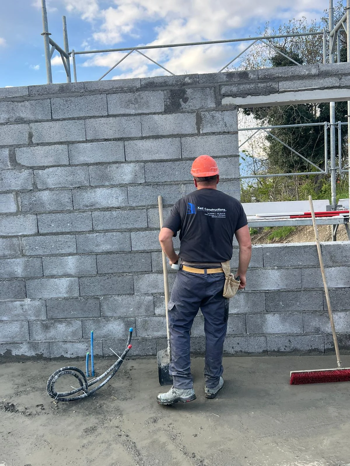 Un membre de l’équipe XETI devant un mur en blocs maçonnés