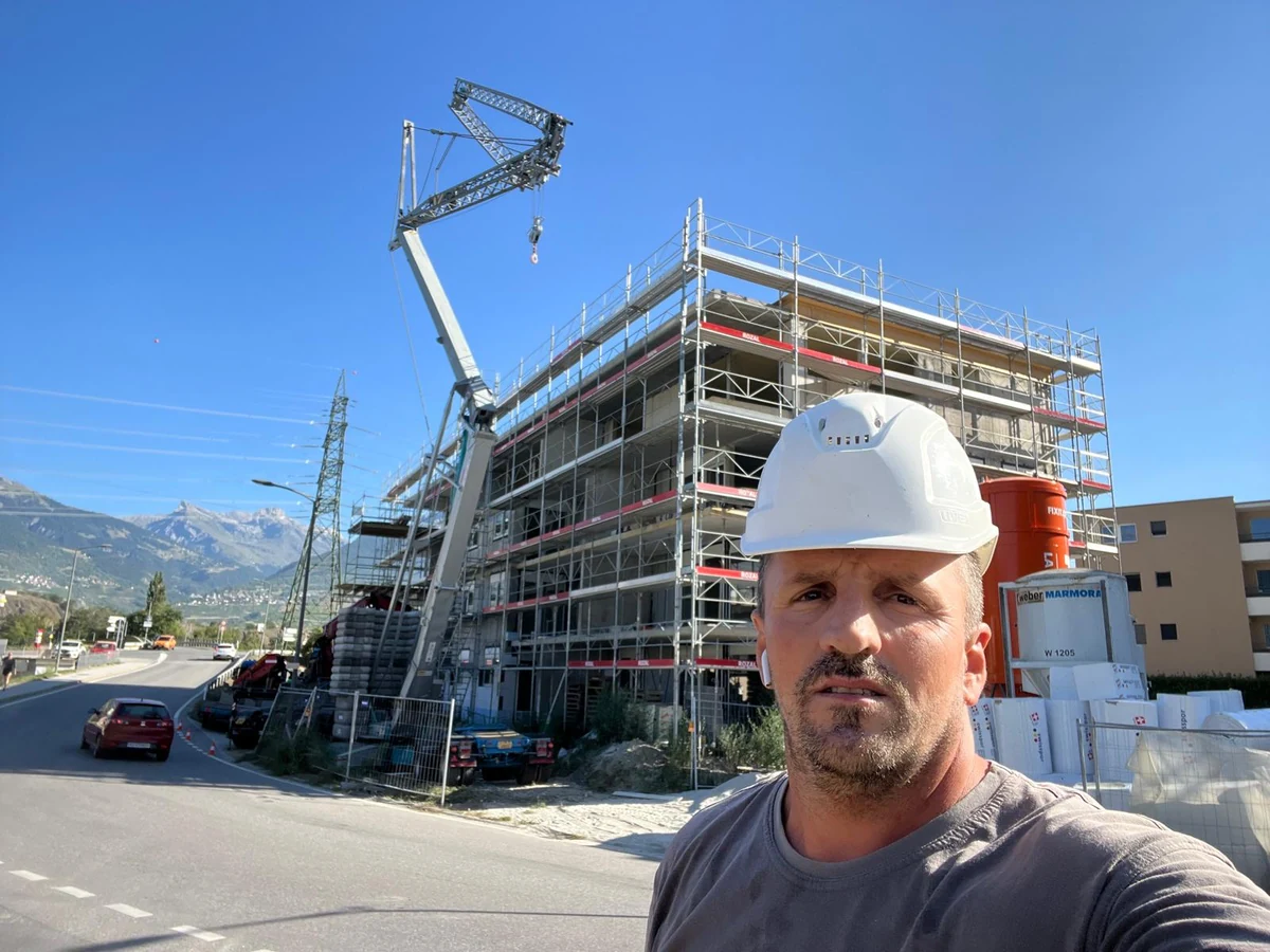 Un professionnel XETI portant un casque blanc devant un immeuble en construction